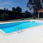 Piscina com água azul cristalina num dia soalheiro, com um enorme ambiente de verão