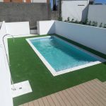 Piscina com água azul cristalina rodeada por relva, criando o perfeito ambiente de verão