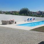 Piscina com agua azul cristalina rodeada por pedra clara