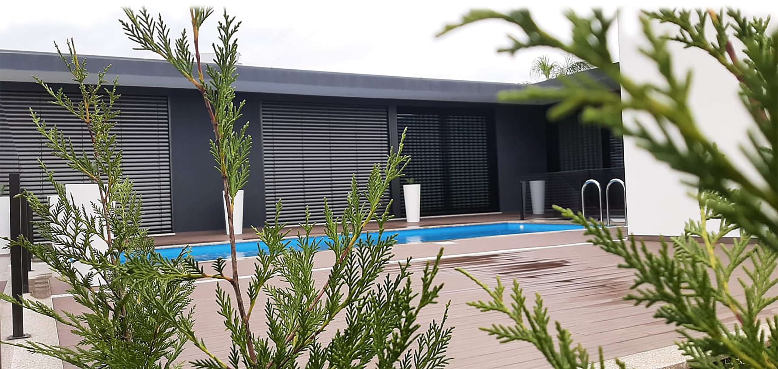 Piscina exterior com água azul cristalina por piso de pedra clara, alinhado ao sol com folhas de árvores a criar uma paisagem bonita de verão