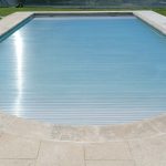 Piscina grande com design moderno, rodeada por pavimento cinzento, criando um visual minimalista e elegante ao ar livre