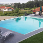 Piscina com água cristalina rodeada de espreguiçadeiras ao por do sol criando um ambiente descontraído