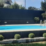 Piscina com água azul cristalina, rodeada de arbustos verdes