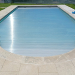 Piscina grande com design moderno, rodeada por pavimento cinzento, criando um visual minimalista e elegante ao ar livre